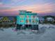 Stunning turquoise beachfront home with multi-level balconies offering panoramic sunset views and private beach access at 1699 E Ashley Ave # B, Folly Beach, SC 29439