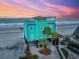 Beachfront home with a turquoise exterior, multiple stories, and stunning ocean views at sunset at 1699 E Ashley Ave # B, Folly Beach, SC 29439