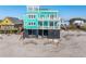 Stunning coastal home with a teal exterior, multiple balconies, and built on stilts for beachside living at 1699 E Ashley Ave # B, Folly Beach, SC 29439