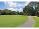 A lush green golf course is bordered by mature trees under a sunny sky, with a path in view at 236 Driftwood Ln, Edisto Island, SC 29438