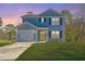 Charming two-story home with light blue siding, a well-manicured lawn, and attached garage at sunset at 3405 Painswick Rd, Johns Island, SC 29455
