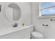 Bathroom vanity with white cabinets, framed round mirror, and natural light from window with blinds at 415 Parkdale Dr # 12B, Charleston, SC 29414