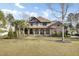 Expansive two-story home boasts a covered front porch, manicured lawn, and lush palm trees, offering curb appeal at 4162 Club Course Dr, North Charleston, SC 29420