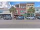 Street view of commercial buildings with palm trees and parallel parked cars at 487 King St # 201, Charleston, SC 29403