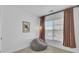 Neutral-toned bedroom featuring a gray beanbag chair, light fixture, and large window with curtains at 5124 E Liberty Park Cir, North Charleston, SC 29405