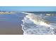 Scenic beachfront with gentle waves lapping onto the sandy shore on a beautiful sunny day at 7600 Palmetto Drive # D-222, Isle of Palms, SC 29451