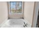 Bright bathroom with a large soaking tub and window overlooking outdoor scenery at 8585 Refuge Pointe Cir, North Charleston, SC 29420