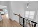 Bright hallway upstairs shows staircase with safety gate, hardwood floors, and doorway to the a bedroom at 8585 Refuge Pointe Cir, North Charleston, SC 29420