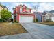 Lovely red two-story home with a well-maintained lawn and an attached two car garage at 8849 Kellum Dr, North Charleston, SC 29420