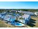 Aerial view showcases coastal homes and a community pool surrounded by lush green landscape near the ocean at 94 W 2Nd St, Folly Beach, SC 29439