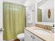 Well-lit bathroom features a vanity with sink, decorative mirror, and a shower with a green patterned curtain at 94 W 2Nd St, Folly Beach, SC 29439
