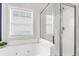 A bright bathroom with a whirlpool tub, a glass-enclosed shower, and a window at 94 W 2Nd St, Folly Beach, SC 29439