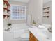 Well-lit bathroom featuring a soaking tub, decorative window, single sink vanity, and ample shelving at 109 Nelson Ct, Summerville, SC 29485