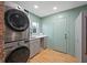 Bright laundry room features stacked washer/dryer, gray cabinets, sink, and stylish wooden flooring at 1115 O T Wallace Blvd, Moncks Corner, SC 29461