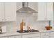 Gourmet kitchen featuring stainless steel hood, gas cooktop, subway tile backsplash, and quartz countertops at 1156 Darling St, Summerville, SC 29485