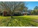 A lush front yard with a large tree shading a brick home with attached garage at 1423 Fairfield Ave, Charleston, SC 29407