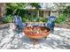 Firepit with seating and view of a home's exterior framed by mature trees and lush flowering plants at 1714 Middle St, Sullivans Island, SC 29482