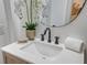 Modern bathroom with sleek sink and black faucet, elegant floral arrangement, and round mirror at 1714 Middle St, Sullivans Island, SC 29482