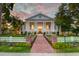 Stunning two-story home featuring classic architectural details, a brick walkway, and an expansive front lawn at sunset at 1714 Middle St, Sullivans Island, SC 29482