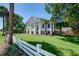 Beautiful two-story home with white columns, a manicured lawn, and a white picket fence at 1714 Middle St, Sullivans Island, SC 29482