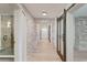 Hallway with hardwood floors and exposed brick walls leads to a bathroom with glass shower at 1714 Middle St, Sullivans Island, SC 29482