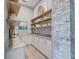 Walk-in pantry featuring marble countertops, custom cabinetry, open shelving, and brick accent wall at 1714 Middle St, Sullivans Island, SC 29482