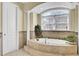A bright bathroom showcasing a garden tub with tile surround, a window with natural light, and decorative plants at 1739 Indigo Island Dr, Hanahan, SC 29410