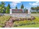 A welcoming Pine Hills neighborhood entrance sign, framed with colorful flowers and verdant landscaping at 202 N Light Way, Summerville, SC 29486