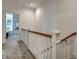 Hallway with white railings and wood trim, leading to a light-filled room with a rocking chair and shuttered windows at 2028 Ironstone Aly, Charleston, SC 29407
