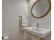 Well-lit powder room with modern fixtures, pedestal sink, and round mirror at 2028 Ironstone Aly, Charleston, SC 29407