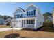 Beautifully landscaped corner lot with a light blue two-story home with a welcoming front porch at 221 Waning Way, Charleston, SC 29492