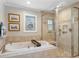 Bathroom featuring a soaking tub, glass-enclosed shower, neutral tile, and a window for natural light at 316 Anadale Ct, North Charleston, SC 29418