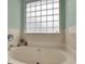 Well-lit bathroom with an beige tub and glass block window allowing privacy and natural light at 3545 Rookwood Pl, Johns Island, SC 29455