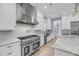 Bright kitchen featuring a stainless steel range hood, gas range, white cabinets, marble counters and backsplash at 4070 Egret Perch Ct, Ravenel, SC 29470