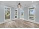 Bright and airy living room with elegant light fixture, large windows, and stylish wood flooring at 4070 Egret Perch Ct, Ravenel, SC 29470