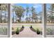 A scenic view from the porch featuring a brick pathway and lush greenery beyond the stately columns at 4070 Egret Perch Ct, Ravenel, SC 29470