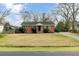 Charming single-story brick home with a well-manicured lawn, mature trees, and a blue sky backdrop at 4203 Marilyn Dr, North Charleston, SC 29418