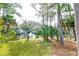 Scenic backyard view featuring lush green grass, mature trees, and a serene pond with a fountain at 482 Sea Cloud Cir, Edisto Island, SC 29438
