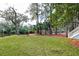 Secluded backyard with a red chair, lush green grass, mature trees, and waterfront access at 482 Sea Cloud Cir, Edisto Island, SC 29438