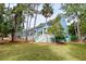 Charming blue multi-story home with white stairs and railings, surrounded by lush trees and well-maintained lawn at 482 Sea Cloud Cir, Edisto Island, SC 29438