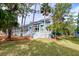 Charming blue multi-story home with white stairs and railings, surrounded by lush trees and well-maintained lawn at 482 Sea Cloud Cir, Edisto Island, SC 29438