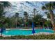 Outdoor community swimming pool surrounded by lush landscaping and lounge chairs with blue umbrellas at 482 Sea Cloud Cir, Edisto Island, SC 29438