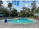 Outdoor community swimming pool with brick paver surround and multiple lounge chairs with blue umbrellas at 482 Sea Cloud Cir, Edisto Island, SC 29438