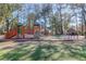 Community playground with swings, slides, and climbing structures, surrounded by mature trees and natural landscaping at 635 Fair Spring Dr, Charleston, SC 29414