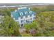 Aerial shot showcasing a charming three-story home with a green roof, surrounded by lush trees and landscaping at 944 Hammocks Way, Edisto Island, SC 29438