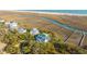 Stunning aerial view of an elegant white home with a green roof near a marsh and beach at 944 Hammocks Way, Edisto Island, SC 29438
