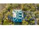 Aerial view showcases the home's unique roof design and inviting outdoor patio area, surrounded by trees at 944 Hammocks Way, Edisto Island, SC 29438
