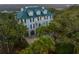 Stately two-story home with a green metal roof and grand entrance surrounded by mature trees and lush landscaping at 944 Hammocks Way, Edisto Island, SC 29438