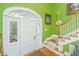 Bright foyer featuring a white front door with decorative glass, complemented by a wooden staircase and green walls at 944 Hammocks Way, Edisto Island, SC 29438
