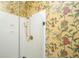Stylish walk-in shower with bright gold fixtures and a floral wallpaper at 944 Hammocks Way, Edisto Island, SC 29438